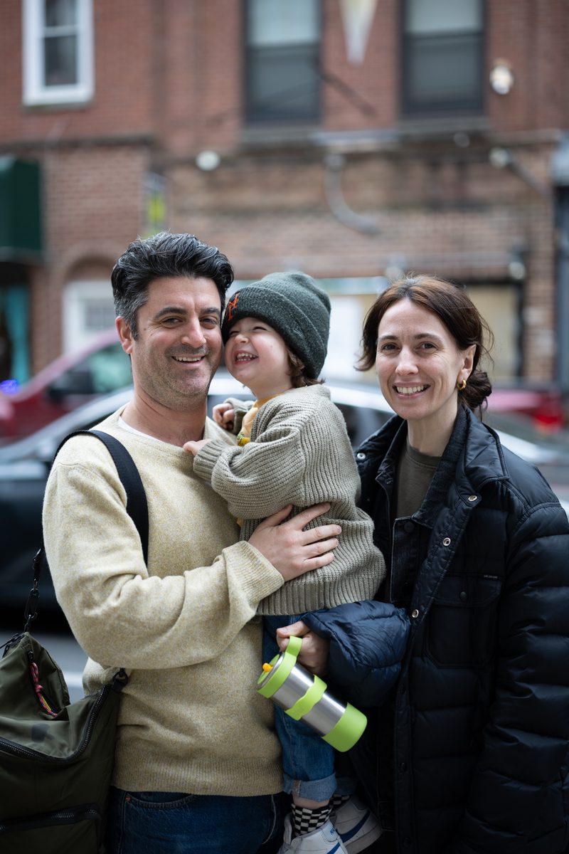 A father holds a toddler in a green knit hat while the mother smiles beside them on South Street.