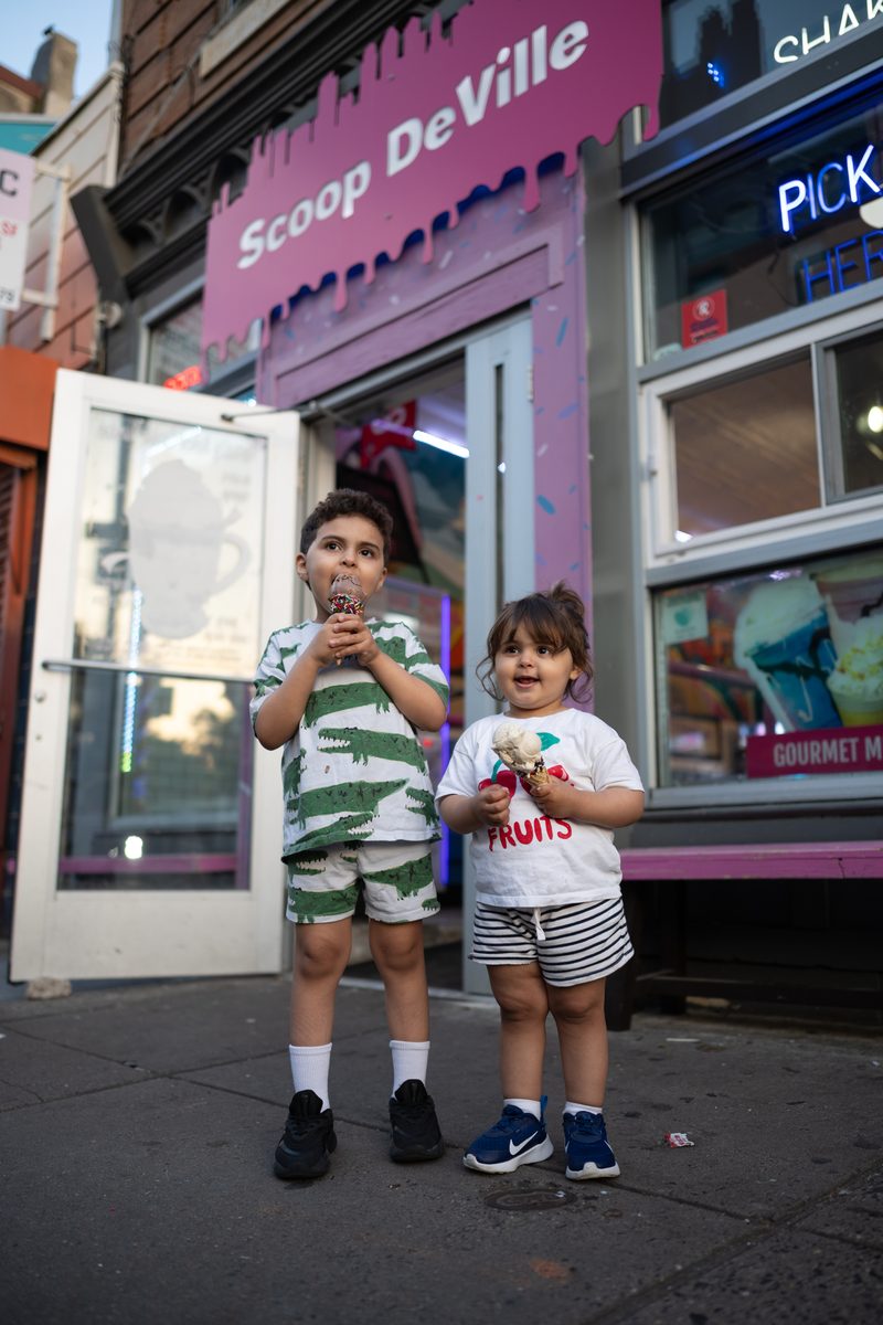 Two young brothers hold ice cream cones outside the pink Scoop DeVille storefront on South Street.