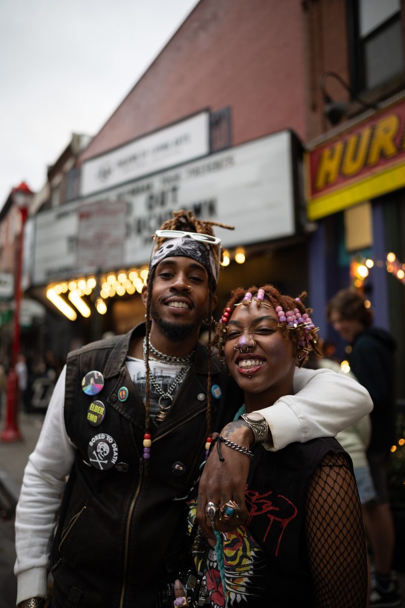 A punk couple in studded vests and pins poses in front of the Theatre of Living Arts marquee on South Street before a show by rapper and singer, Teezo Touchdown.