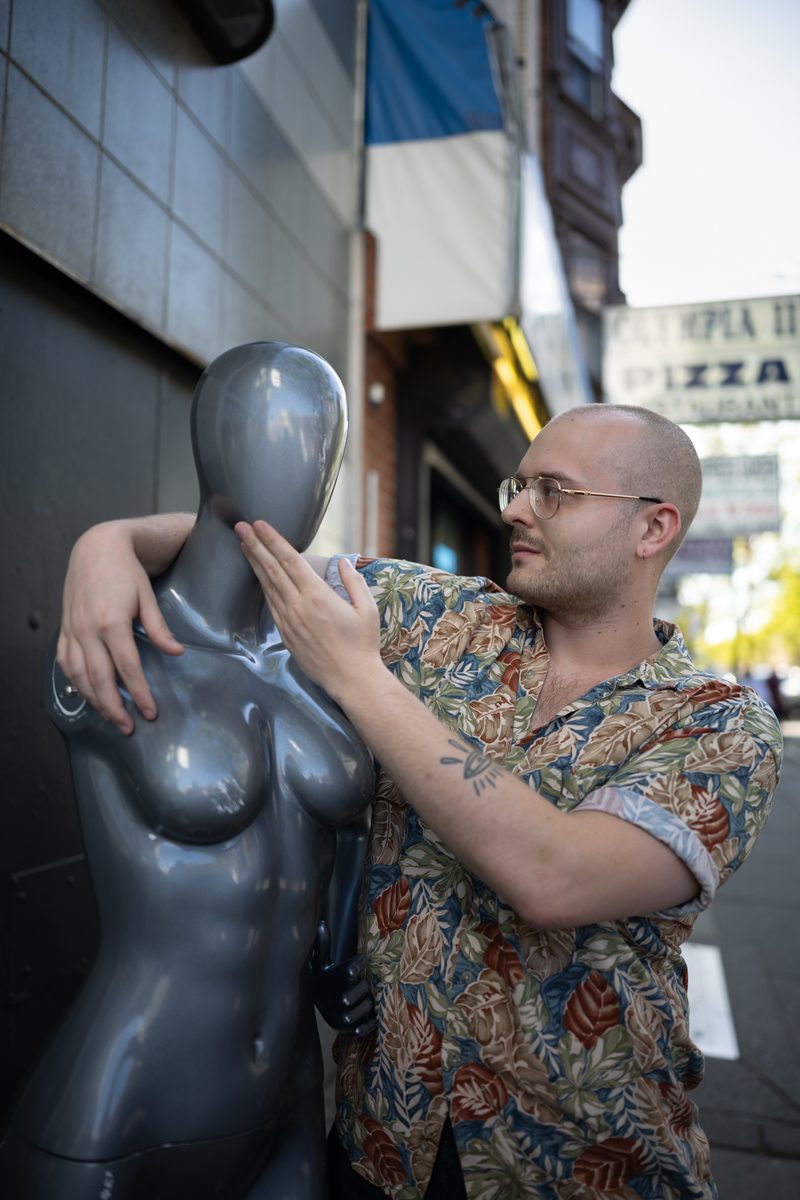 A man in glasses and a Hawaiian shirt poses with his arm around a silver mannequin on South Street.